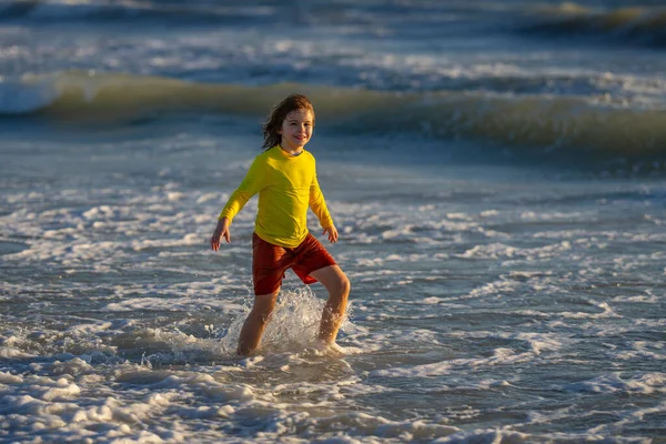 気をつけて海を走っている子供 暖かい夏の日に海の近くを走る幸せなかわいい子供 かわいい子供の男の子が走り 家族の休暇に海や海で飛び散っています ビーチを走っている子供は — ストック写真