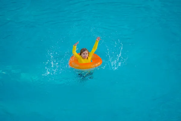 Kid playing with inflatable ring in swimming pool on summer day. Little kid swimming in pool. Kid in swimming pool relax and swim on inflatable ring. Summer vacation concept. Summer vacation