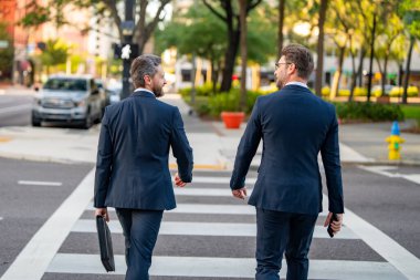 İş adamları şehirde Walkind projesini tartışıyor. İki genç iş adamı şehir manzarası için şehir dışına çıkıyor. İki iş ortağının açık havada buluşması. Takım elbiseli iş adamı açık havada dolaşıyor.