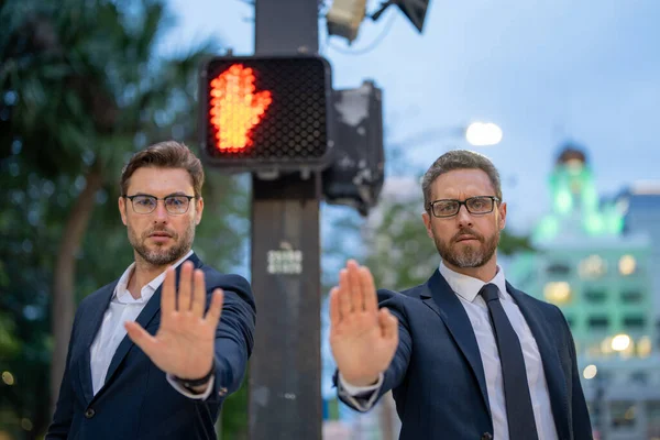 Businessmen doing stop sing with hand. Warning expression with negative and serious gesture. Stop hand gesture, businessman says hold on. Business man holding out hand, indicating stop on street