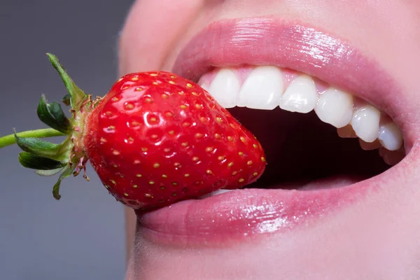 唇にイチゴ 女性の口の中で赤いイチゴを閉じます 白い健康な歯で笑顔の閉鎖 — ストック写真