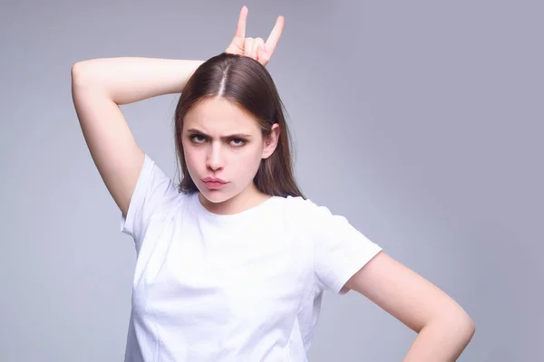 Woman with angry expression. Angry hateful girl furious. Angry rage woman face with finger horn. Anger woman with furious negative emotion portrait. Aggressive and mad girl bad behavior in studio