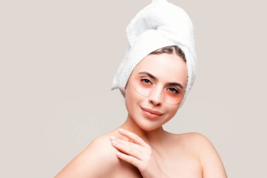 Havlu bantlı genç bir kadın. Göz bandı yapıştıran seksi bir kadın. Kafasında havluyla portre kızı yakın plan. Göz maskeli kozmetik bantlar. Kadının yüzü yakın plan.