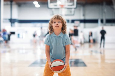 Basketbol çocuk oyunu. Basketbol topu tutan sevimli küçük çocuk skor yapmaya çalışıyor.