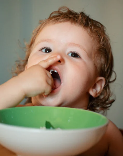 厨房里有趣的小宝宝用手指从盘子里吃东西 有趣的孩子面对特写镜头 — 图库照片