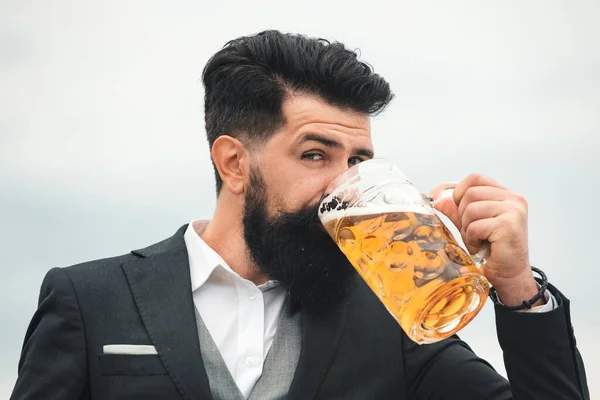 穿着经典西装的男人喝啤酒 穿着经典服装的留着胡子的人看上去很高兴也很满意 带着高脚杯啤酒的人的画像 — 图库照片