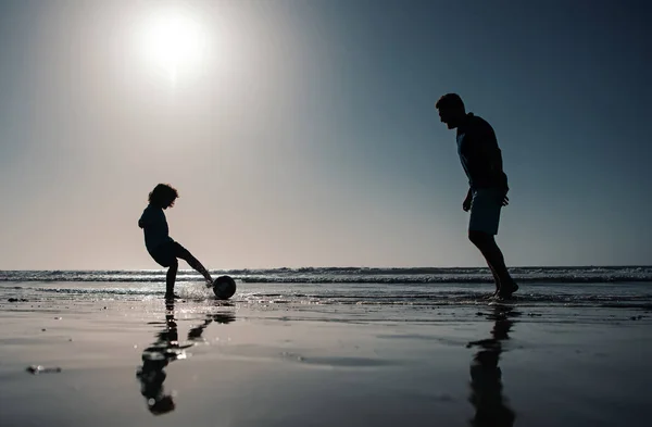 父と息子は夏休みにビーチでサッカーやサッカーをする — ストック写真