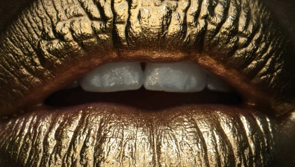 Glamour cosmetic. Gold lips, golden lipgloss on sexy lips, metallic mouth. Beauty woman makeup close up