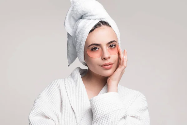 Woman applying eye patches. Close up portrait girl with towel on head. Portrait of beauty woman with eye patches showing an effect of perfect skin. Eyes mask cosmetic patches woman face closeup