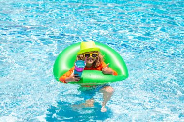 Tatlı komik çocuk yüzme havuzunda oyuncak yüzme yüzüğüyle rahatlıyor yaz tatilinde tropikal bir otelde eğleniyor. Deniz kıyısındaki çocuklar