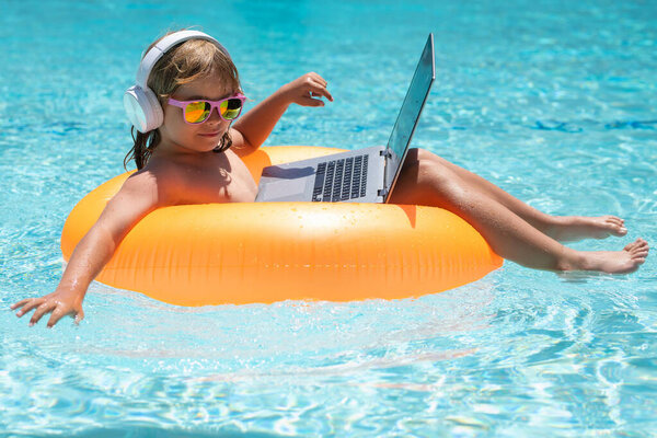 Working and relax on the beach. Child working on laptop computer at poolside swimming pool. Summer online technology