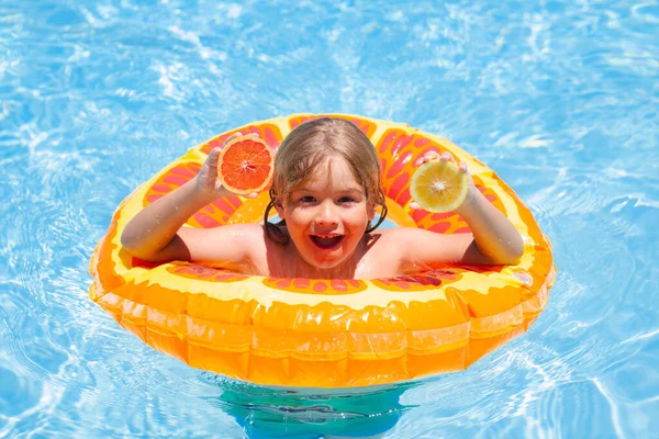 游泳池里有橙子的孩子夏天的水果暑假的时候 小男孩在游泳池里漂浮着 快乐的孩子在游泳池里玩游泳圈 — 图库照片