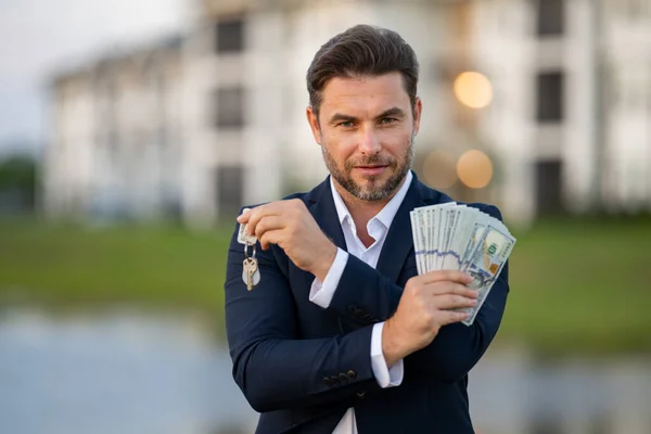 House owner, real estate agents hold money dollars and house keys. Housing estates, buying and selling housing estates. Man celebrating new purchase buying real estate. Mortgage concept
