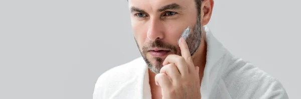 美男のバナー顔クリームを適用する美しい男の肖像画 男性のための保湿スキンケアクリーム 皮膚のリフティングやアンチエイジング効果のためのマスク 美容男性の顔の概念 スキンケアとエイジング — ストック写真