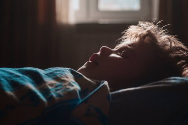 Yatakta uyuyan çocuk. Sabah ışıkları