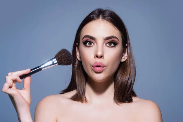 Woman applying foundation powder or blush with makeup brush. Facial treatment, perfect skin, natural make up, facial beauty. Isolated on studio background. Applying makeup