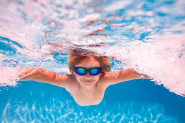 Çocuk havuzda oynuyor. Çocuklar tatil ve tatil konsepti. Yaz çocuğu yüzme havuzunda oynuyor. Havuzda suyun altında küçük bir çocuk. Çocuklar yaz tatilinde havuzda yüzerler.
