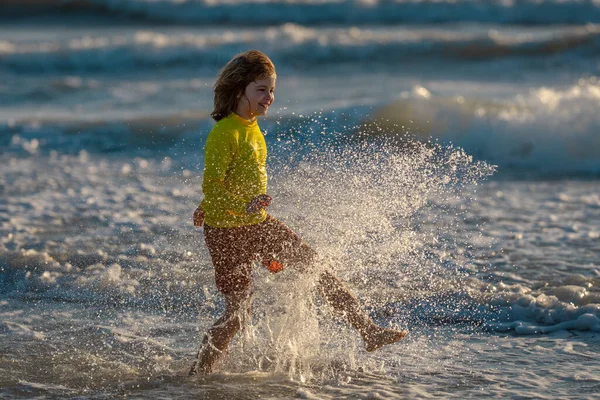 夏休みに海の水の中に走っている子供 海沿いを走る子供の少年 夏のビーチで子供 子供は海の水でレースを実行します 子供は海の水に沿って走る 海の夏休みの子供 — ストック写真