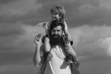 Baba ve oğlu çocuk çocuk dışarıda oynuyor. Mutlu baba, oğluna yazın gökyüzüne geri dönüyor. Ebeveyn -lik. Mutlu baba yaz aylarında gökyüzüne oğlu geri binmek veren