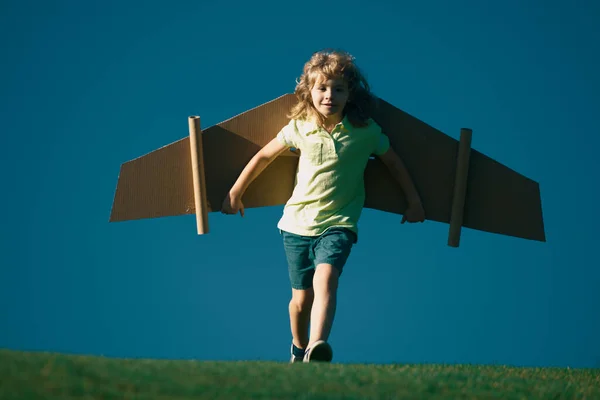 青い空に対しておもちゃの翼を持つパイロットのような子供の男の子 子供の自由の概念 パイロットになる夢 屋外で遊んでおもちゃのジェットパックを持つ子供のパイロット 幸せな子供時代 子供の夢 — ストック写真