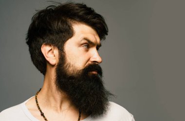 Gri arka planda izole edilmiş iş adamının portresi. Sakallı adam ifadeyle düşünüyor. Yakışıklı erkek model, yakın çekim yüzü.