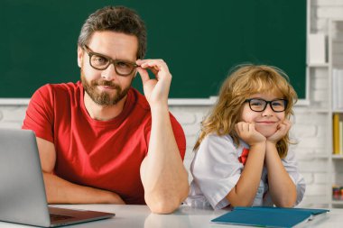 Öğretmen ve çocuk okulda öğreniyor. Komik ilkokul çocuğu.