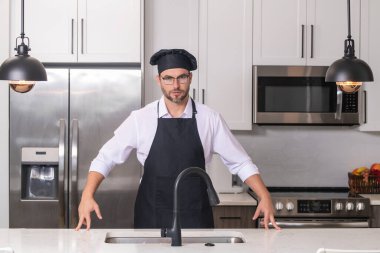 Yemek pişirme ve aşçılık konsepti. Mutfakta üniformalı aşçı. Erkek aşçı ya da önlüklü aşçı. Aşçının bereli portresi. Yemek pişirme konsepti