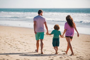 Aile güneşli bir günde kumsala yürüyor.