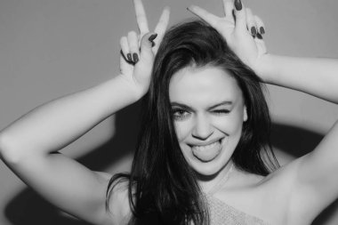 Genç bir kadın boynuzları gibi parmaklarıyla komik jestler yapıyor. Çılgın komik seksi kız boynuzları gibi parmaklarıyla komik jestler yapıyor. Boynuzlarını gösteren kadın