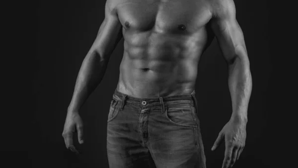 Muscle strong man guy in jeans on gray isolated background. Ideal fit body. Fashion portrait of strong brutal guy. Muscular sexy man with torso