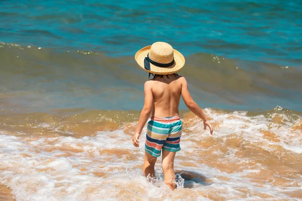 海の波の中で男の子の子供のバックビュー 水の海のスプラッシュで再生します 夏休み — ストック写真