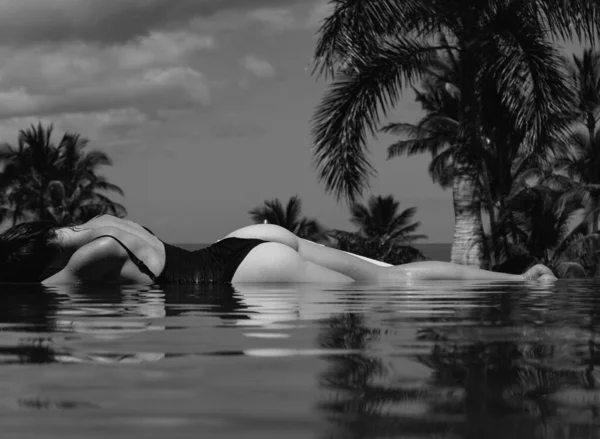 無限のスイミングプールの女性 スパスイミングプールでリラックスしたセクシーな女の子 幸福感 夏休みのコンセプト — ストック写真