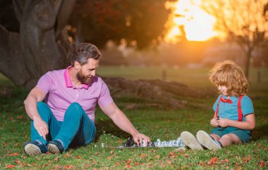 Baba oğluyla satranç oynar. Aktif insanlar parkta satranç oynayıp eğleniyorlar. Çocukla vakit geçiriyorlar. Aile dışı oyun