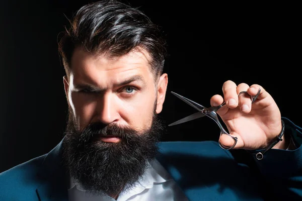 Bearded man, portrait of man with long beard and moustache. Barber scissors for barber shop. Vintage barbershop, shaving. Brutal serious male with modern hairstyle on black
