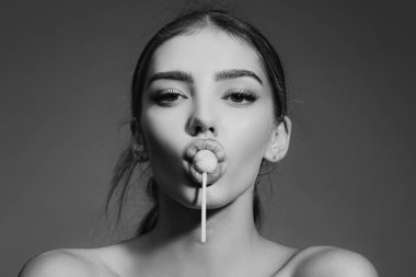 Şehvetli, çekici bir bayan kırmızı dudaklı, lezzetli şekerli lolipopları yalıyor. Kız lolipop emiyor. Seksi kadın pop sanatı tarzında flört ediyor. Seksi kadın portresi