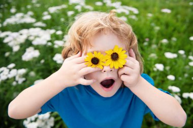 Komik çocuk dışarıda eğleniyor. Çocuk yaz parkında oynuyor. Yeşil çimlerin üzerinde küçük bir çocuk