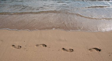 Tropikal deniz suyu beyaz kumsaldan ayak iziyle geliyor.