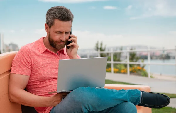 Bilgisayarla Çalışan Yakışıklı Genç Işadamı Dışarıda Cep Telefonuyla Konuşuyor — Stok fotoğraf