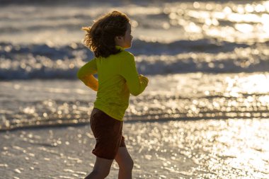 Denizde oynayan heyecanlı çocuk. Çocuk dışarıda eğleniyor. Yaz tatili ve sağlıklı yaşam tarzı konsepti. Yazın kumsalda eğlenen sevimli çocuklar. Denizde oynayan mutlu çocuk. Yaz tatili
