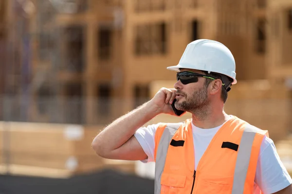 工人用电话 建筑工人用电话休息一下 建筑师用手机 男性建筑工程师 建筑师在一个建筑工地 头戴硬礼帽的工头工头 — 图库照片