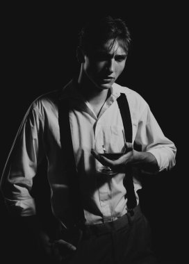 Bardak brendi ya da konyaklı bir adam. Elinde bir bardak viski tutan bir adam. Siyah stüdyoda izole edilmiş viski kadehli bir adamın portresi. Tatma ve degukasyon konsepti. Genç şarap garsonu.