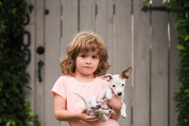 Yavrular ve çocuklar dışarıda. Küçük çocuk küçük bir köpek taşıyor, hassas duygular.