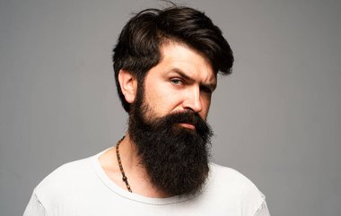 Kendine güvenen ciddi bir adamın portresinin sakalı ve bıyığı var. İş adamı kendini ifade ederek düşünür. Yakışıklı erkek model, yakın çekim yüzü.