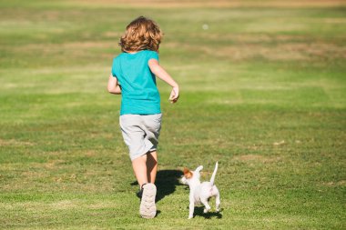 Mutlu çocuk bir köpekle dışarıda koşuyor.