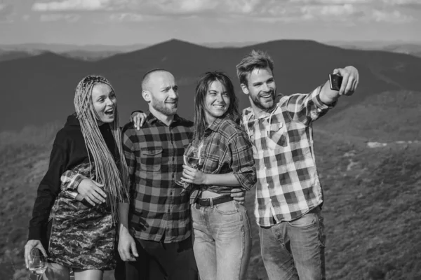 Group of friends taking a selfie in the mountains. Group of hikers takes photo in nature. Camping together is fun, friendship. Students on summer vacation laughing and talking