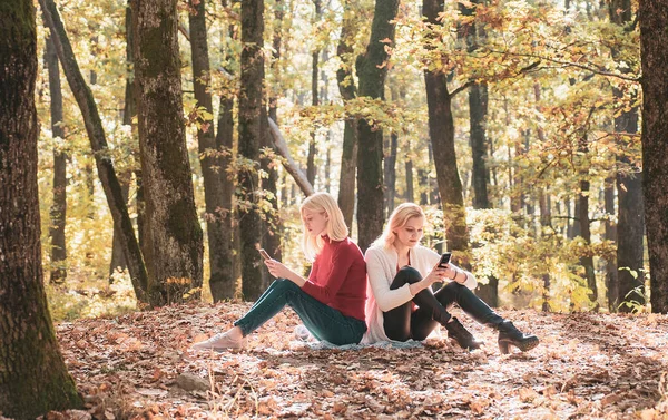 2人の真剣な女の子がスマートフォンの会話をしている 秋の公園で携帯電話を使用して10代の女の子 — ストック写真