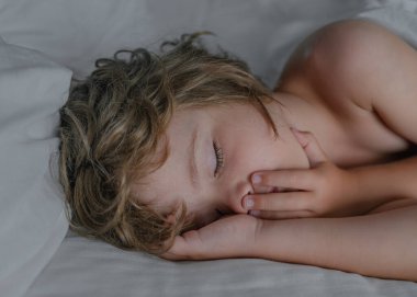 Yatakta uyuyan sevimli çocuklar. Uyuyan küçük çocuğun yakın plan portresi. Küçük melek rüyaları