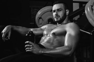 Dinlenme zamanı. Eğitimden sonra yorgun sporcu dinleniyor. Bir şişe suyu ya da proteini olan bir adam. Crossfit, spor ve sağlıklı yaşam tarzı konsepti