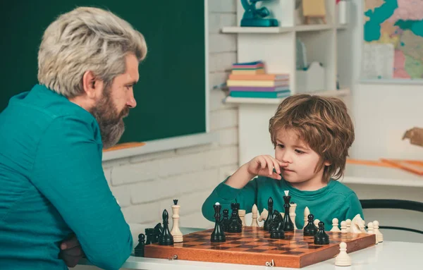 Teacher and kid. Games and activities for children. Teacher and child. Man teacher play chess with preschooler child. Father and son