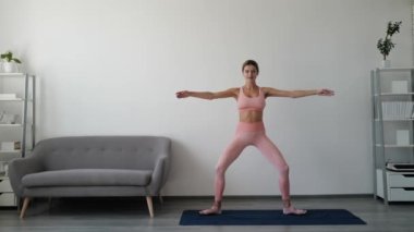 Spor salonundaki kadın esniyor. Genç bir kadın esneme egzersizleri yapıyor. Spor yapan genç bir kadın oturma odasında tek başına egzersiz yapıyor. Sağlıklı vücut yaşam tarzı konsepti için evde egzersiz